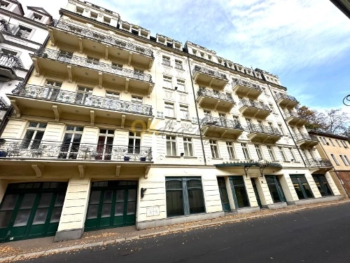 Fotografie fasády bytového domu s balkony na ulici.