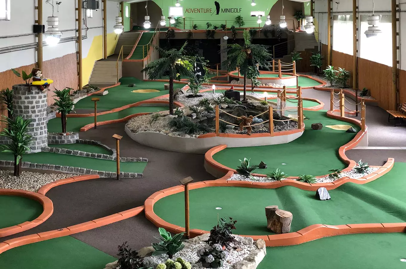 Vnitřní minigolfová dráha s tropickou tematikou a zvířaty.