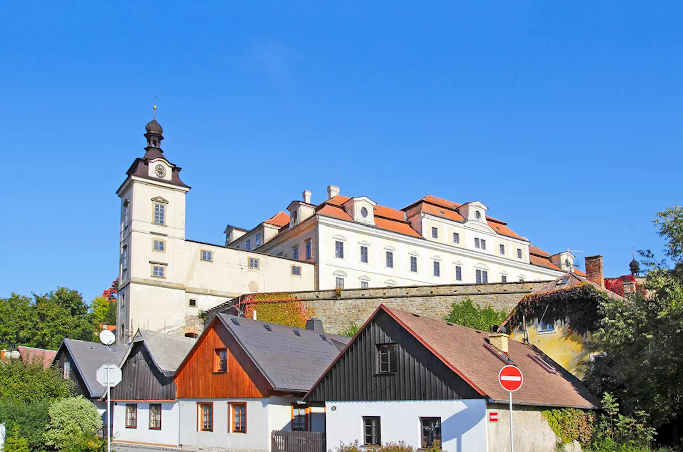 Zámek v Rychnově nad Kněžnou s domy dole pod modrou oblohou.