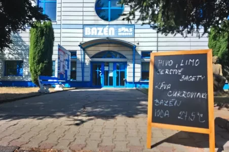 Tabule s nabídkou piva před vstupem do bazénu.
