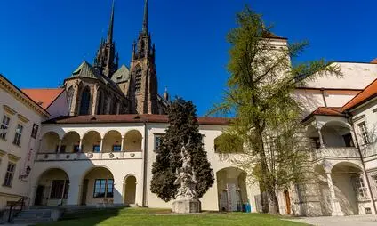 Kostel svatého Petra v Brně s klášterním dvorem pod modrou oblohou.