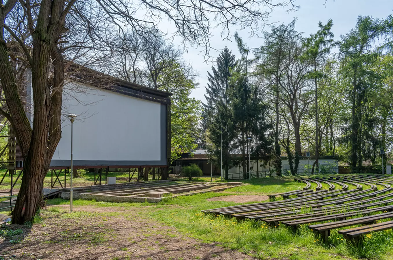 Venkovní kino s řadami lavic před velkou bílou plátnem v parc.