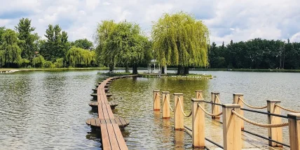 Klidné jezero v parku s dřevěnou chodníčkem.
