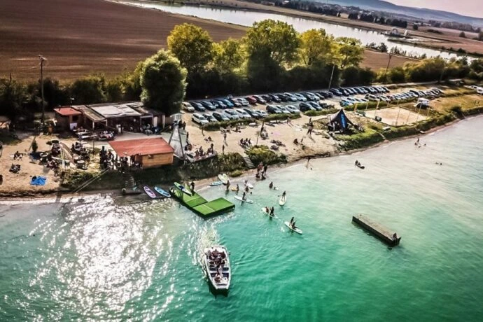 Pohled na pláž s loděmi, auty a lidmi v okolí Velké Bystřice