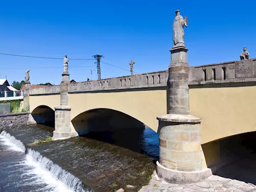 Historický kamenný most s sochami nad řekou ve Vamberku.