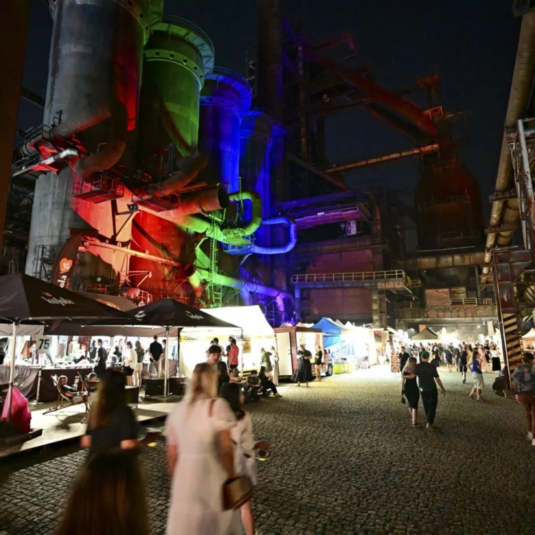 Noční scéna z ostravského festivalu s barevným osvětlením průmyslových budov.