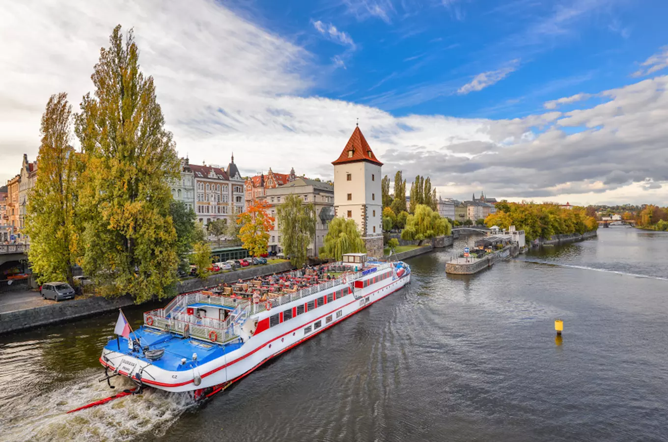 Velká loď s turisty pluje po řece v Praze.
