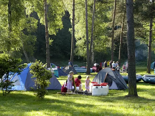 Rodina kempuje v lese s plachtami a nafukovacími čluny.