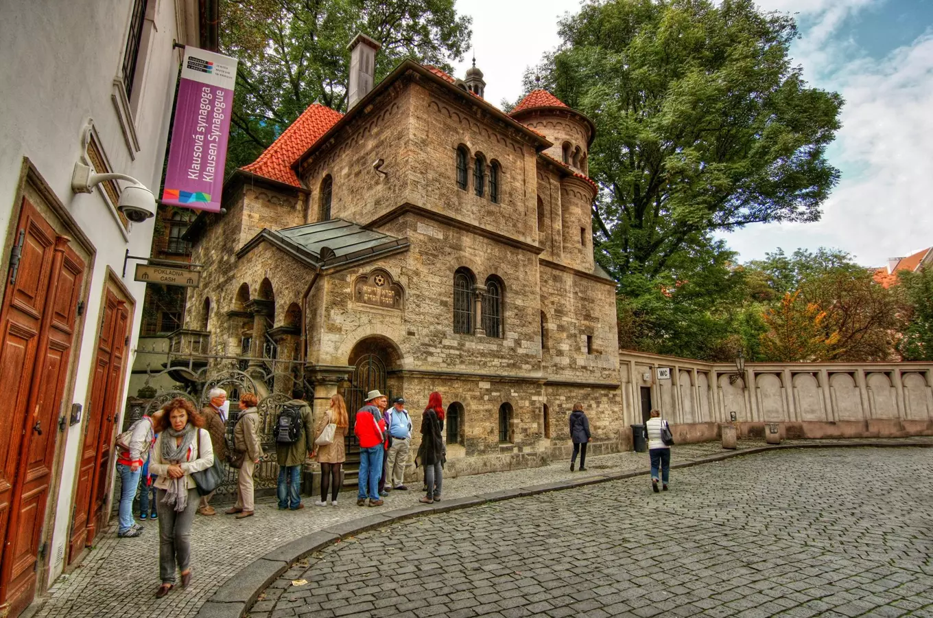 Exteriér synagogy Klause v Praze s turisty před vstupem.