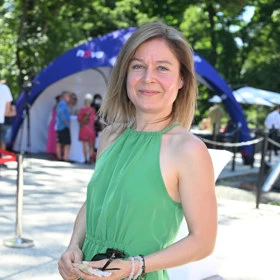 Žena v zeleném šatu na venkovním akci s dětmi.