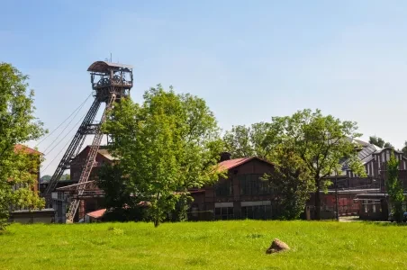 Historická průmyslová budova s dolem v Ostravě na pozadí zelené trávy.