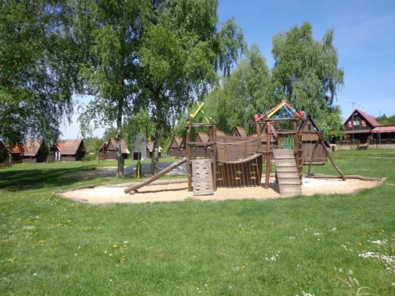Hřiště s dřevěnou hradbou a chatami v pozadí