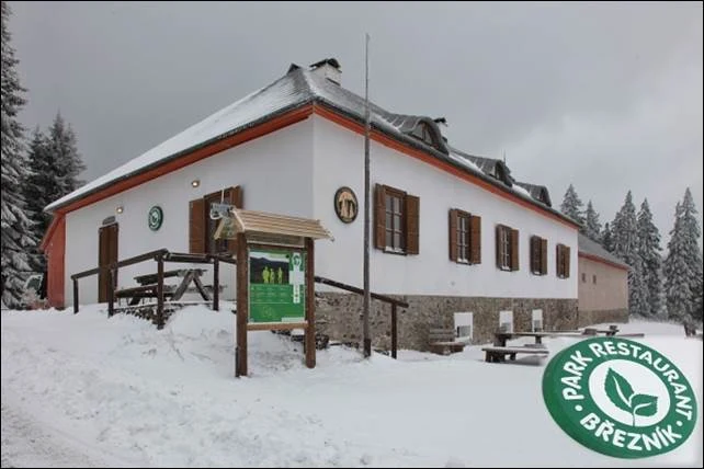 Bílá budova s restaurací v Březníku pod sněhem.