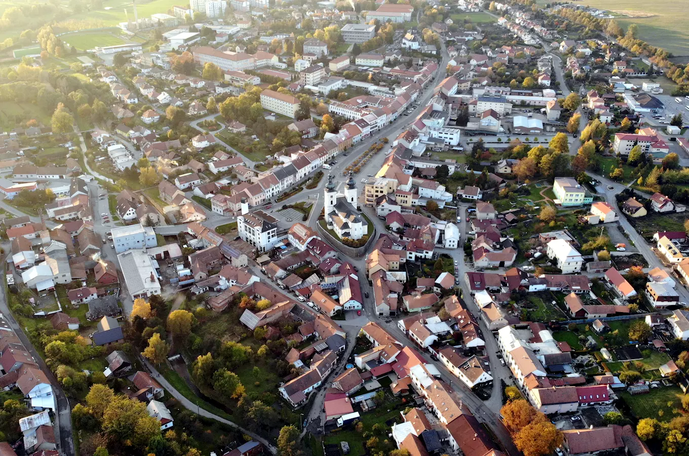 Pohled z letadla na centrum Bystřice nad Pernštejnem s kostelem a historickými domy.