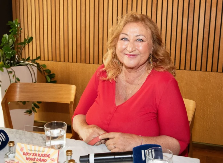 Halina Pawlowská sedí za stolem s mikrofony na akci.