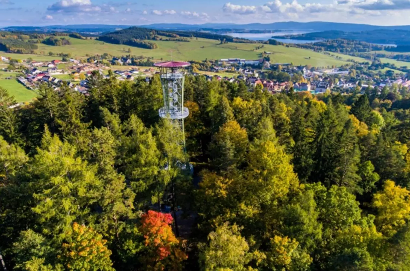 Výhledová rozhledna v lese nad vesnicí s výhledem na krajinu.
