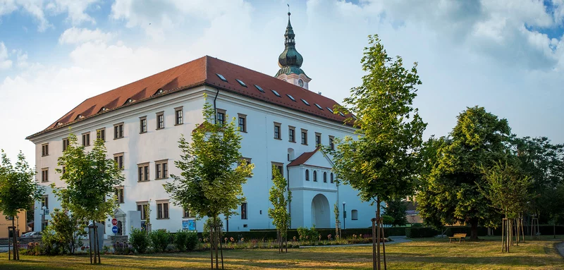 Zámek v Uherském Ostrohu s věží na pozadí modré oblohy.
