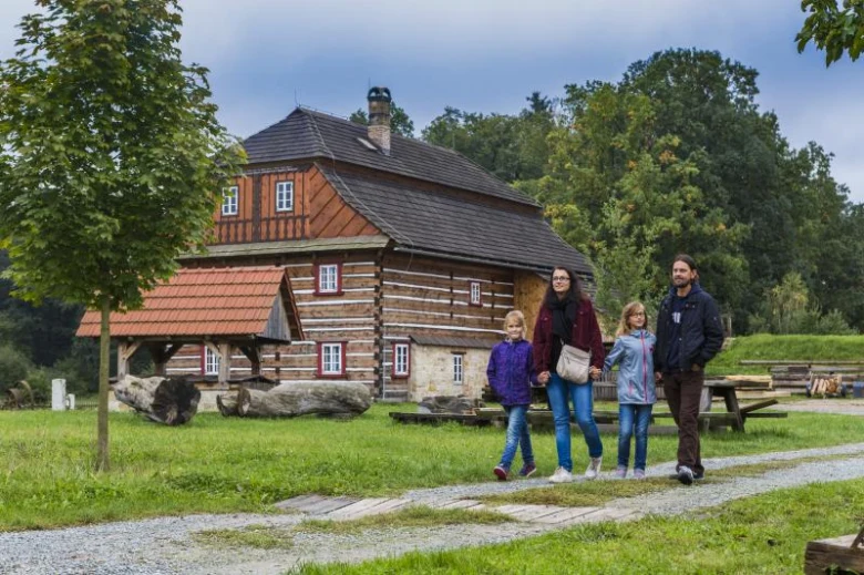 Rodina prochází dřevěnou chalupou v Podorlickém skanzenu Krňovice.