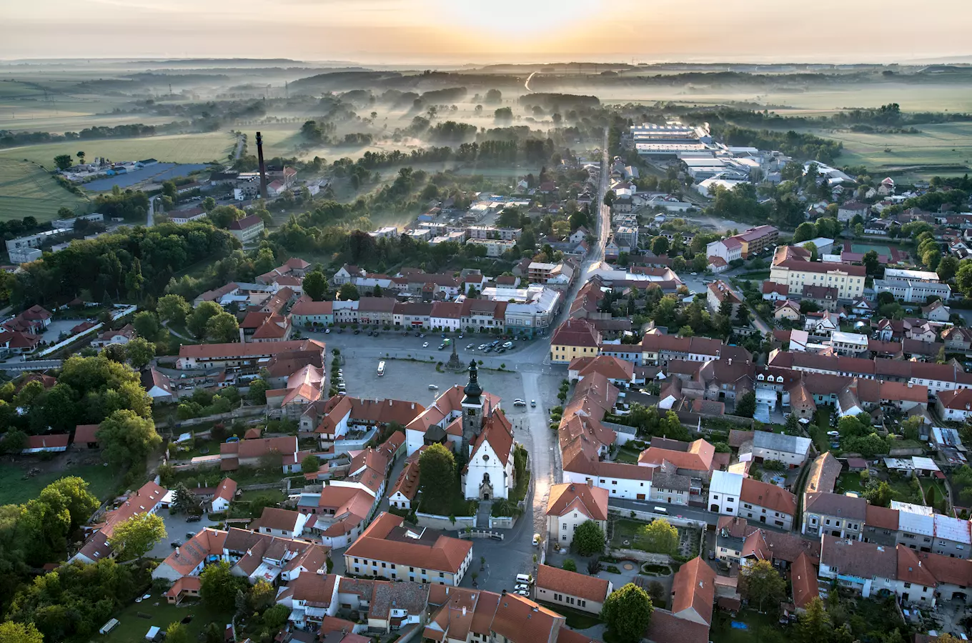 Vzdušný pohled na město Velvary s kostelem a okolní krajinou.