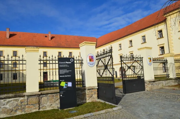 Vstupní brána do města Pacov s historickým domem v pozadí.