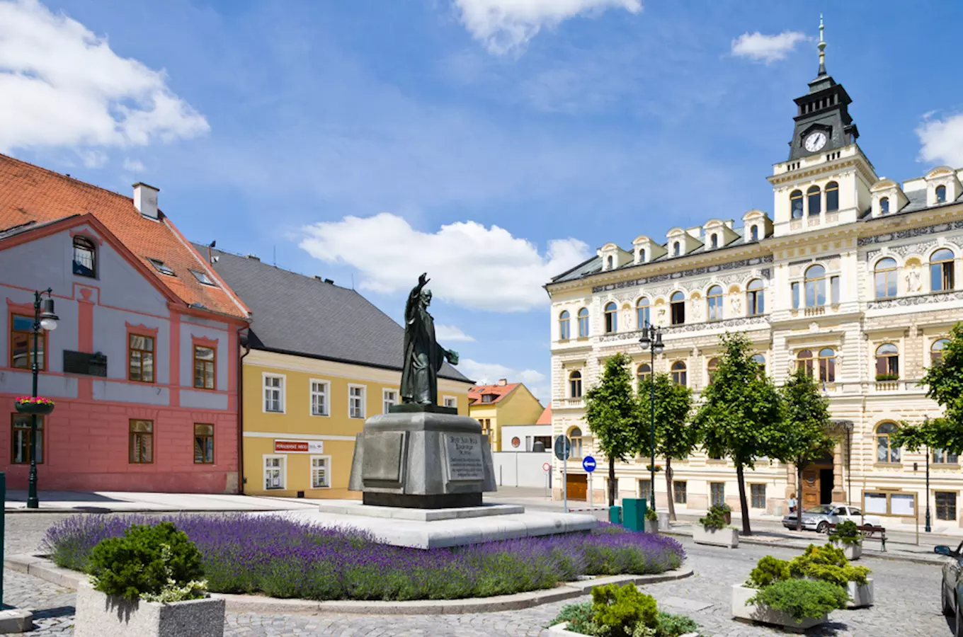 Náměstí v Lounech s pomníkem a historickými budovami.