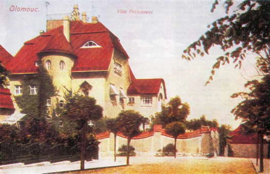 Historická fotografie vily Primavesi s červenou střechou a plíživými rostlinami.