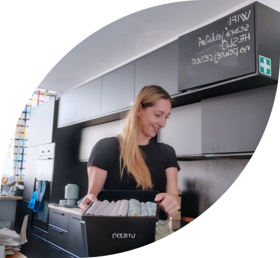Žena uspořádává předměty v krabici na kuchyňském stole.