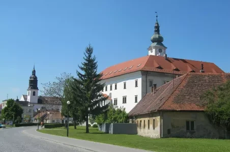 Zámek v Uherském Ostrohu s věžemi pod modrou oblohou.