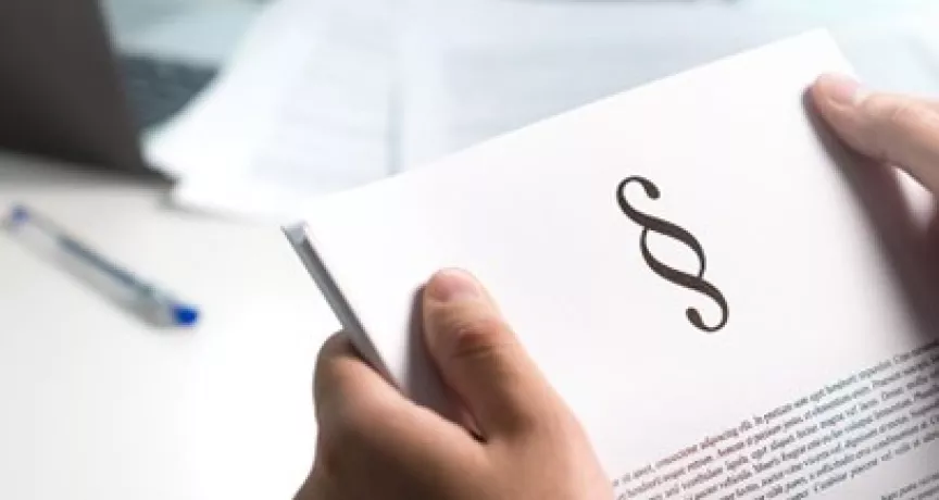 Ruce drží dokument s právním symbolem pro téma výpovědní lhůty.