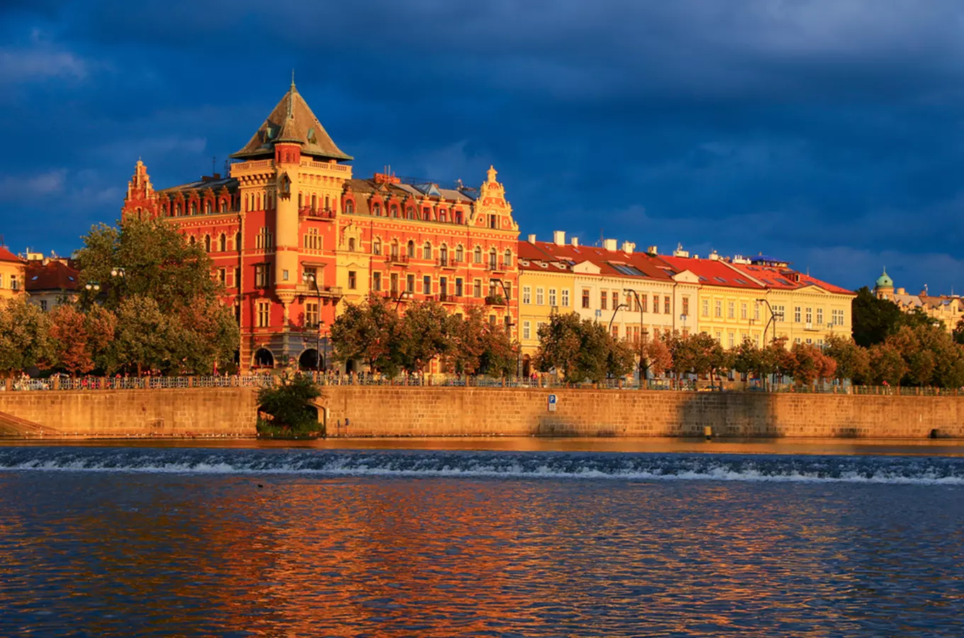 Palác Bellevue v Praze na břehu řeky při západu slunce.
