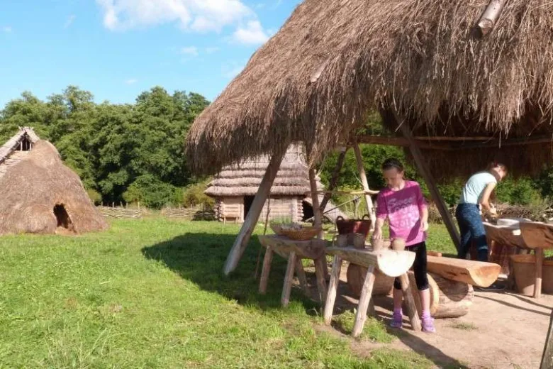 Tradiční stříškované domky venku s lidmi vařícími jídlo.