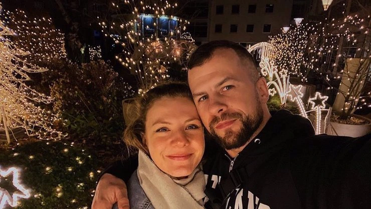 Manželé se fotí před vánočními dekoracemi v noci.