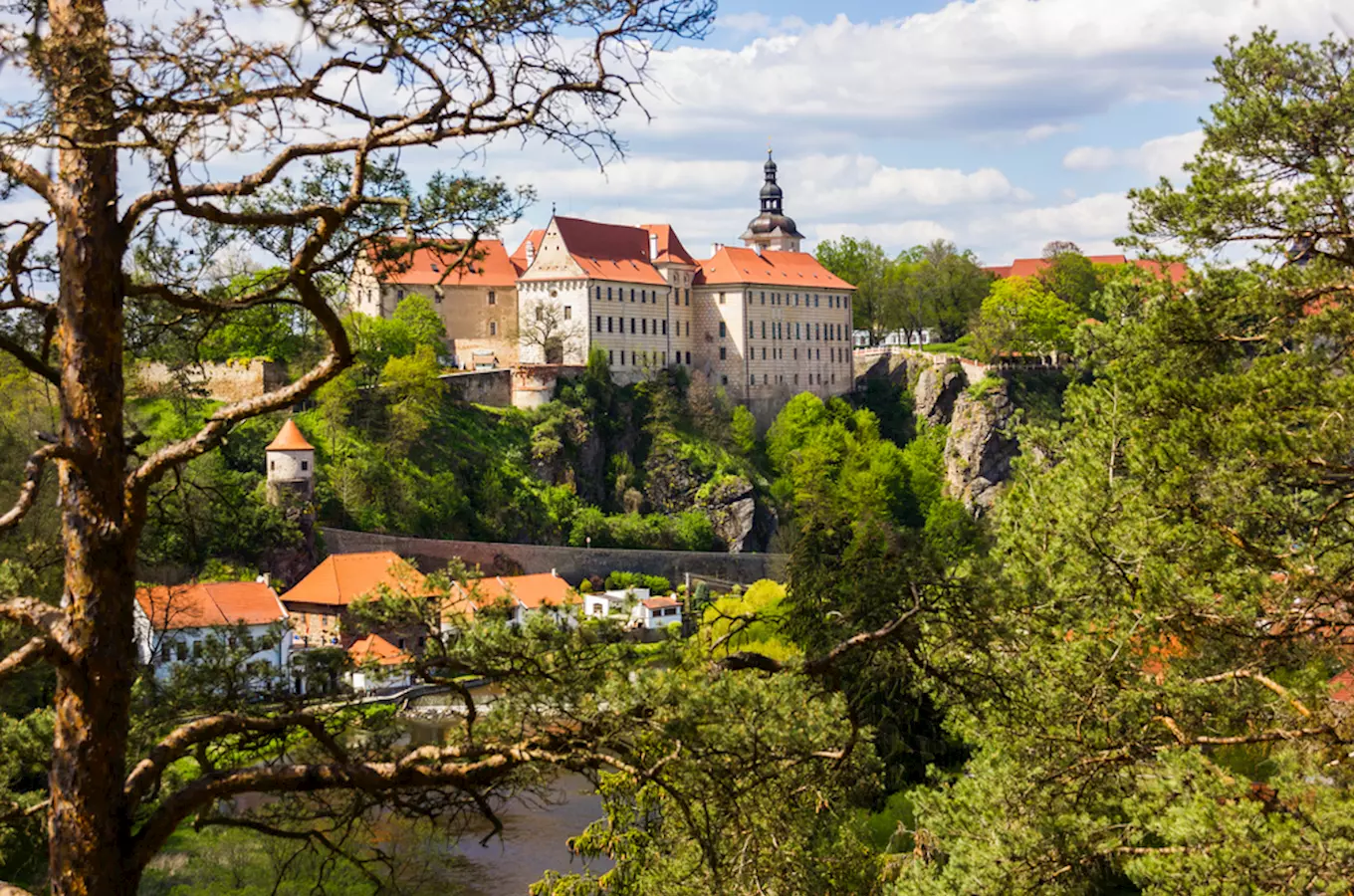 Zámek v Bečyni na skále nad městem s řekou.