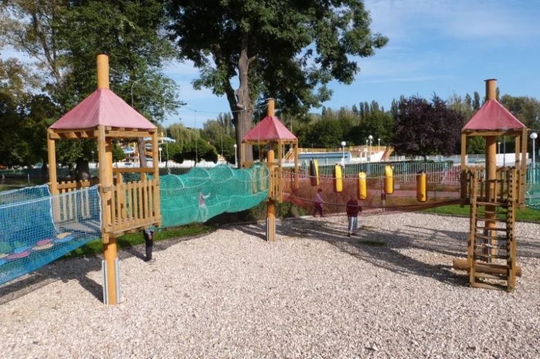 Venkovní hřiště pro děti s dřevěnými konstrukcemi a síťovými mosty.