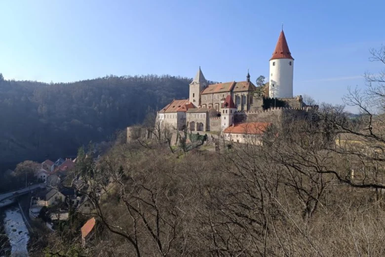 Zámek na kopci s věží nad vesnicí v českém krajině.