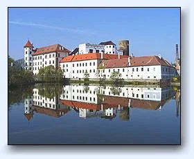 Zámek Jindřichův Hradec s odrazem v řece pod modrou oblohou.