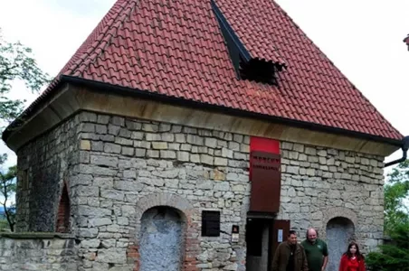 Stará kamenná věž s červenou střechou v Žatci.