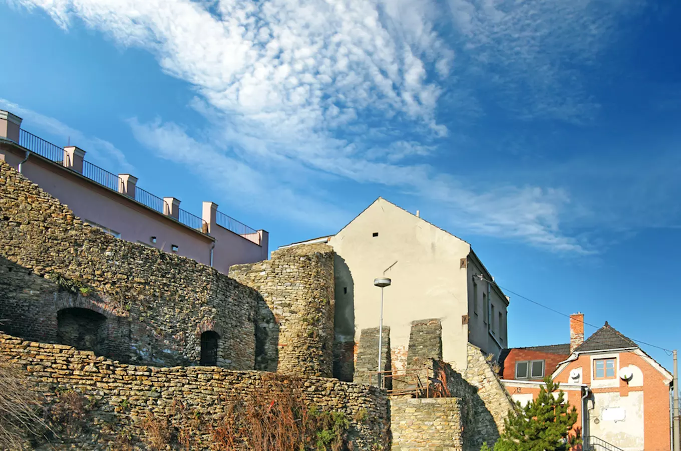 Ruiny hradu v Přerově s okolními domy pod modrou oblohou.