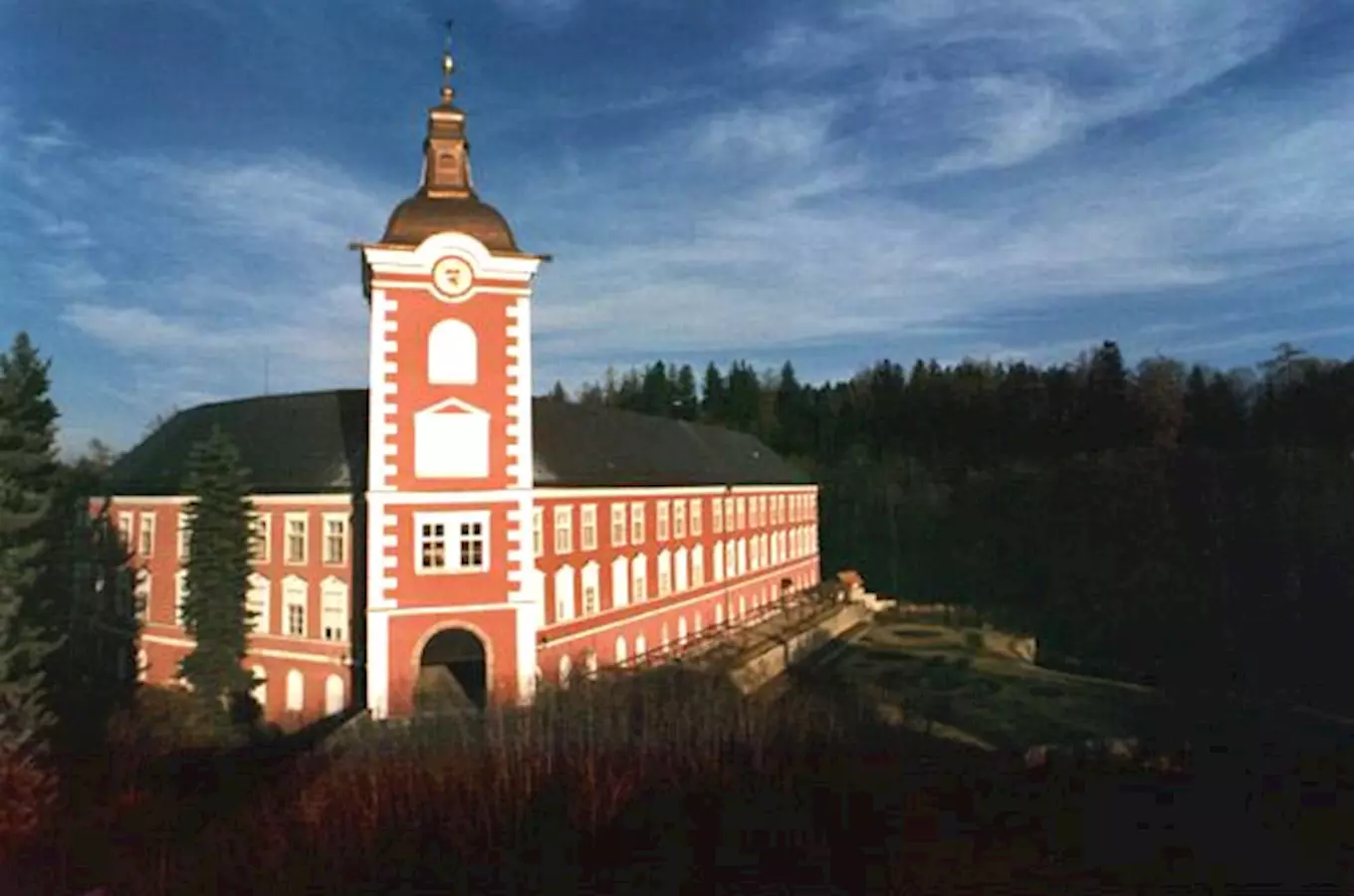Zámek Kamenice nad Lipou s věží na kopci pod modrou oblohou.