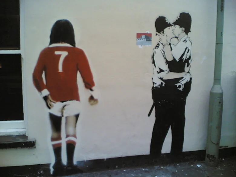 Banksy grafiti na zdi s policisty líbajícími se.