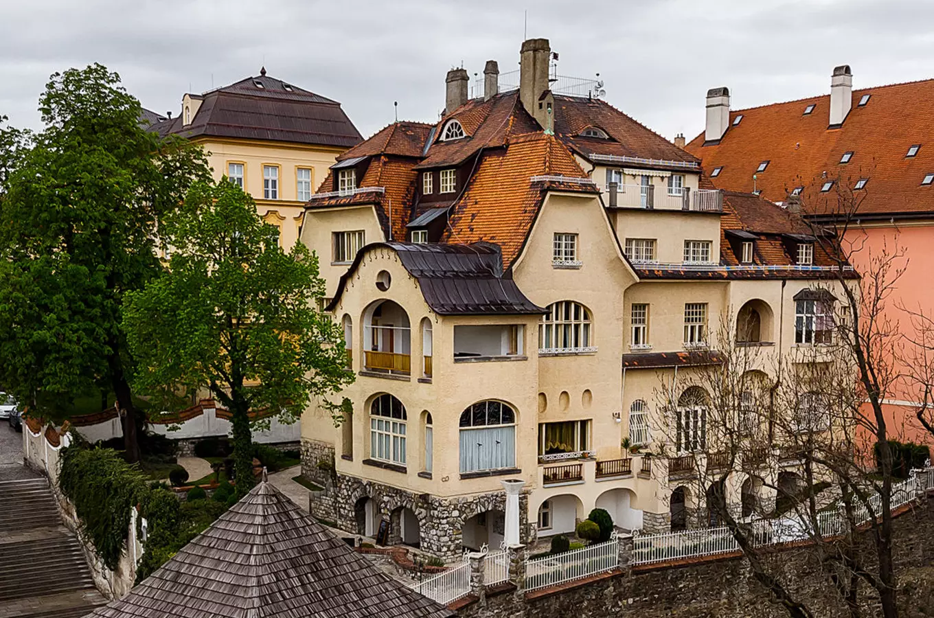Fotografie žluté Vily Primavesi v Českém Krumlově s kamenným základem.
