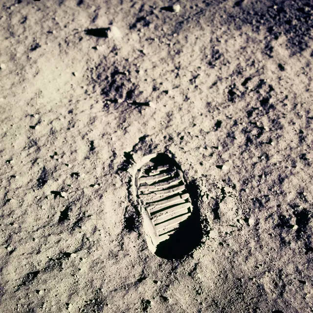 Stopa kosmonauta v měsíčním prachu s ostrým stínem.