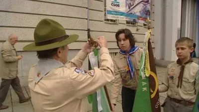 Skautský vůdce s dvěma chlapci v uniformě u vlajek.