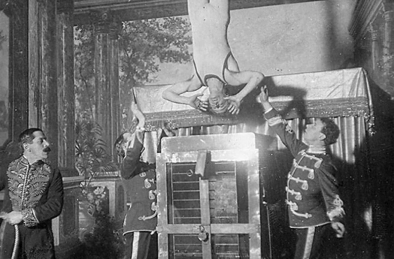 Harry Houdini unikající z pouta ve výstupu s asistenty.