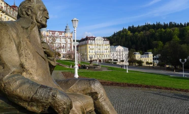 Bronzová socha muže sedícího na náměstí v Mariánských Lázních