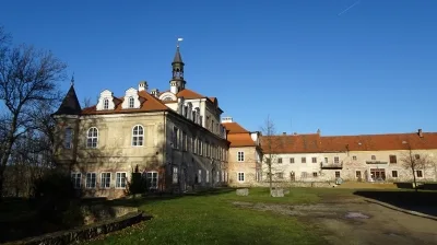 Zámek Svinaře s věží na modré obloze v areálu.