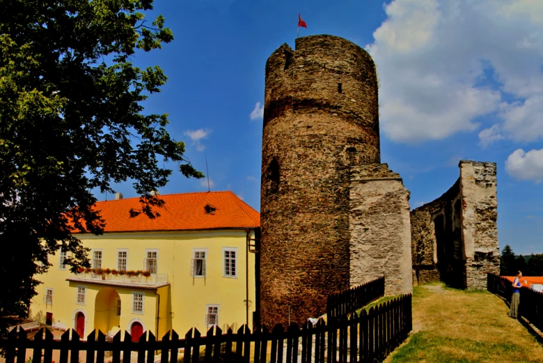 Zřícenina hradu Svojanov s věží a žlutou budovou.