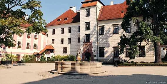 Historický zámek v areálu s fontánou na nádvoří.