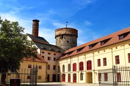 Dvůr hradu v Táboře s věží a budovami pod modrou oblohou.