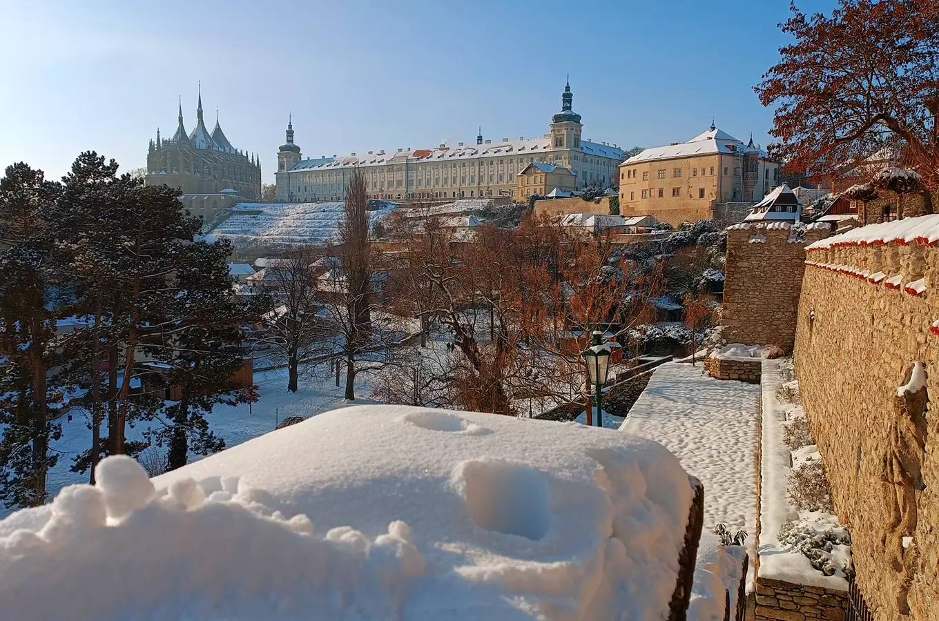 Zimní pohled na Pražský hrad pokrytý sněhem pod modrou oblohou.